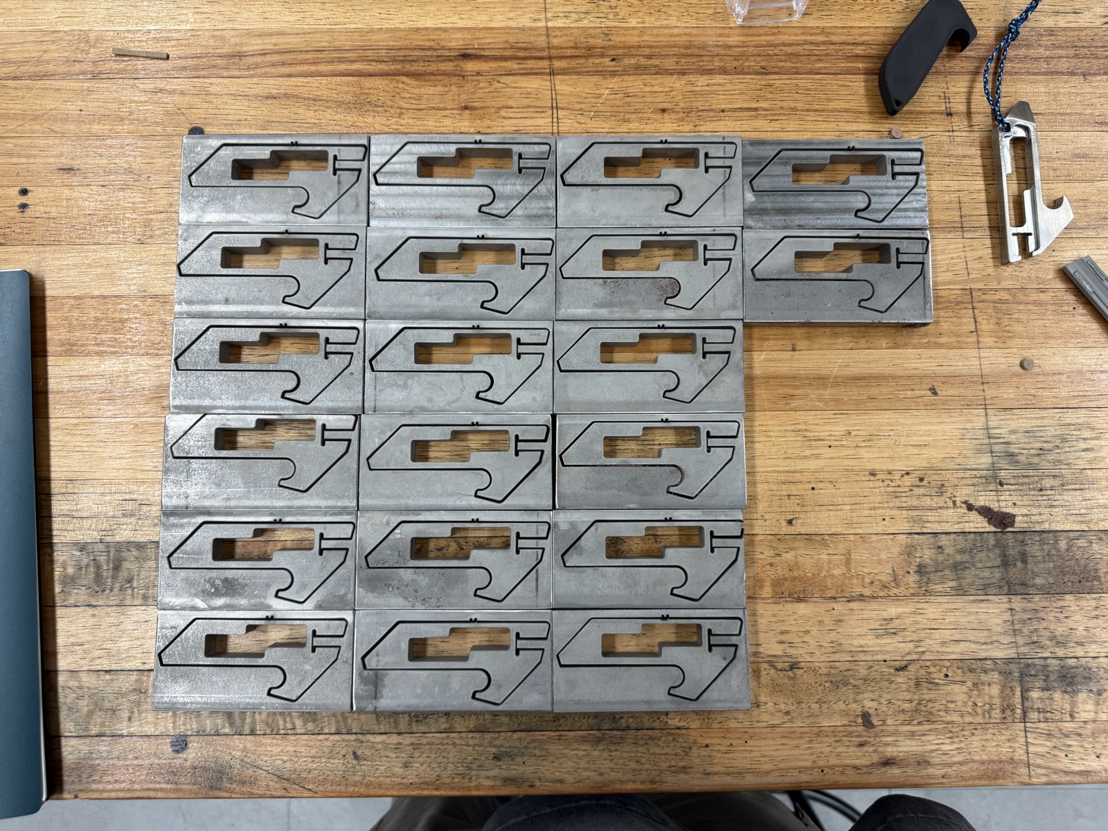 Batch of waterjetted aluminum bodies laid out on workbench